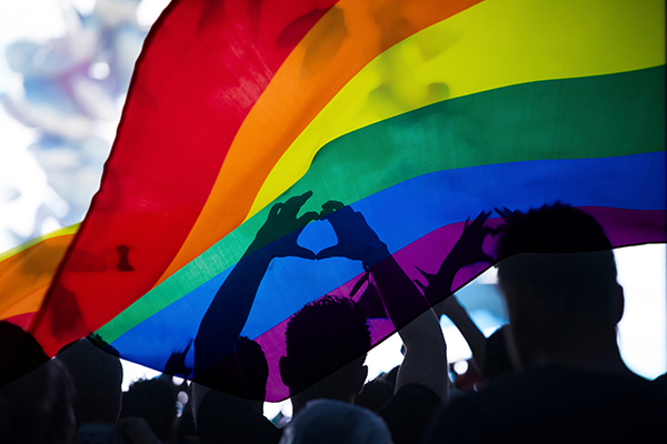 Pride community at a parade with hands raised and the LGBT flag - symbol of love and tolerance