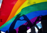 Pride community at a parade with hands raised and the LGBT flag - symbol of love and tolerance