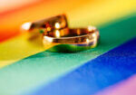 Two gold wedding rings on rainbow lgbt flag. Homosexual marriage. Lgbt rights and law